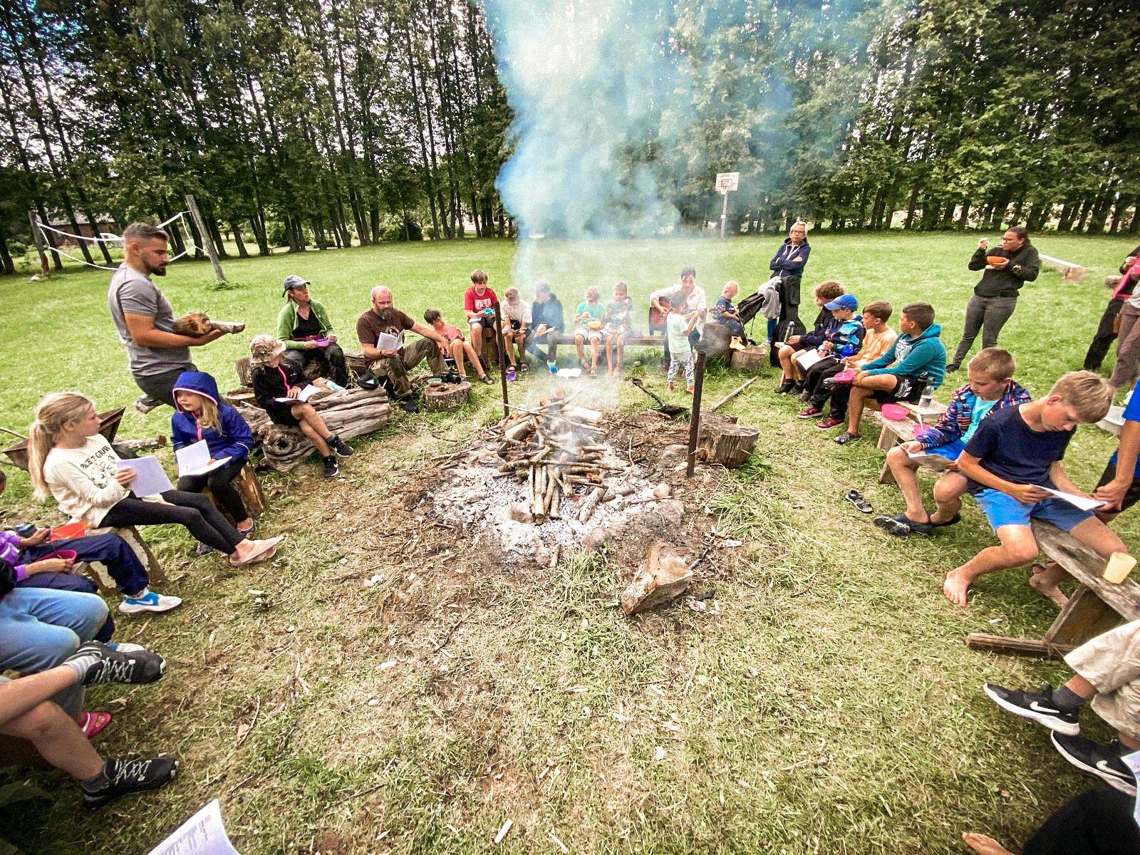Die Lagergruppe sitzt mit Liederblättern im Kreis ums Feuer.